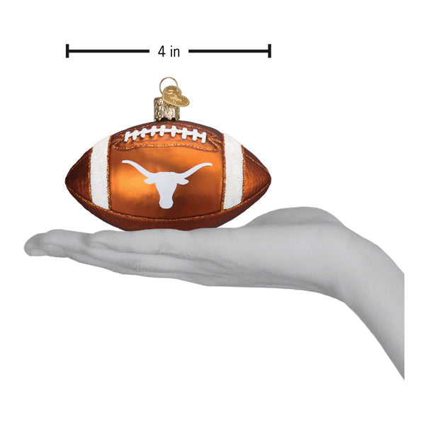Burnt orange glass football ornament featuring the white Texas Longhorns logo, held in a hand for scale.