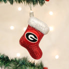 Red glittery Georgia Bulldogs stocking ornament with a white faux fur cuff hanging on a Christmas tree.