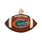 Glass Florida Gators football ornament featuring a brown textured finish, white glitter laces, and the team logo.