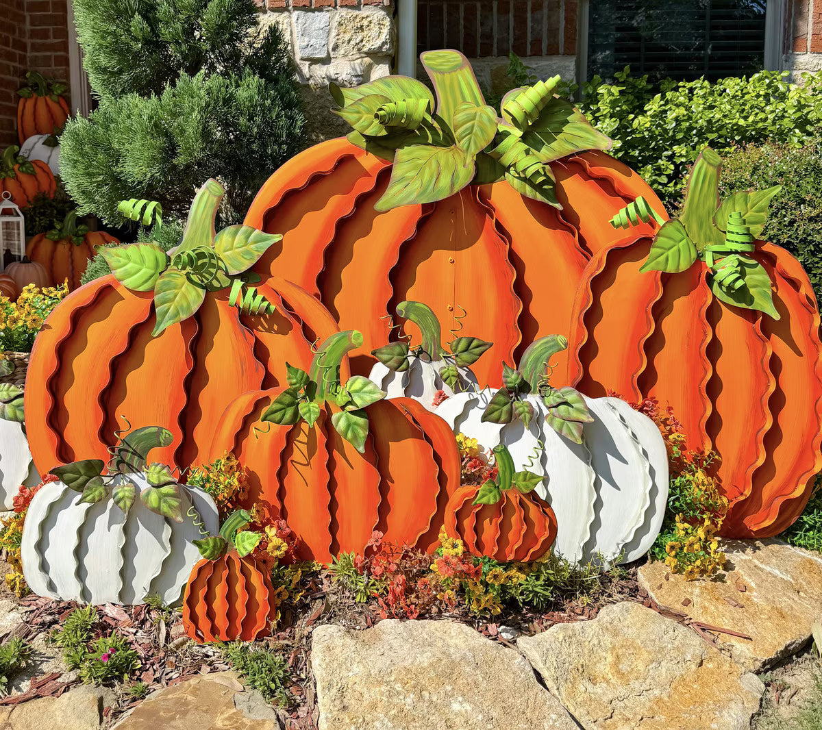 Set of two orange metal ribbon pumpkins with green leaves, designed for tabletop or outdoor fall decor.