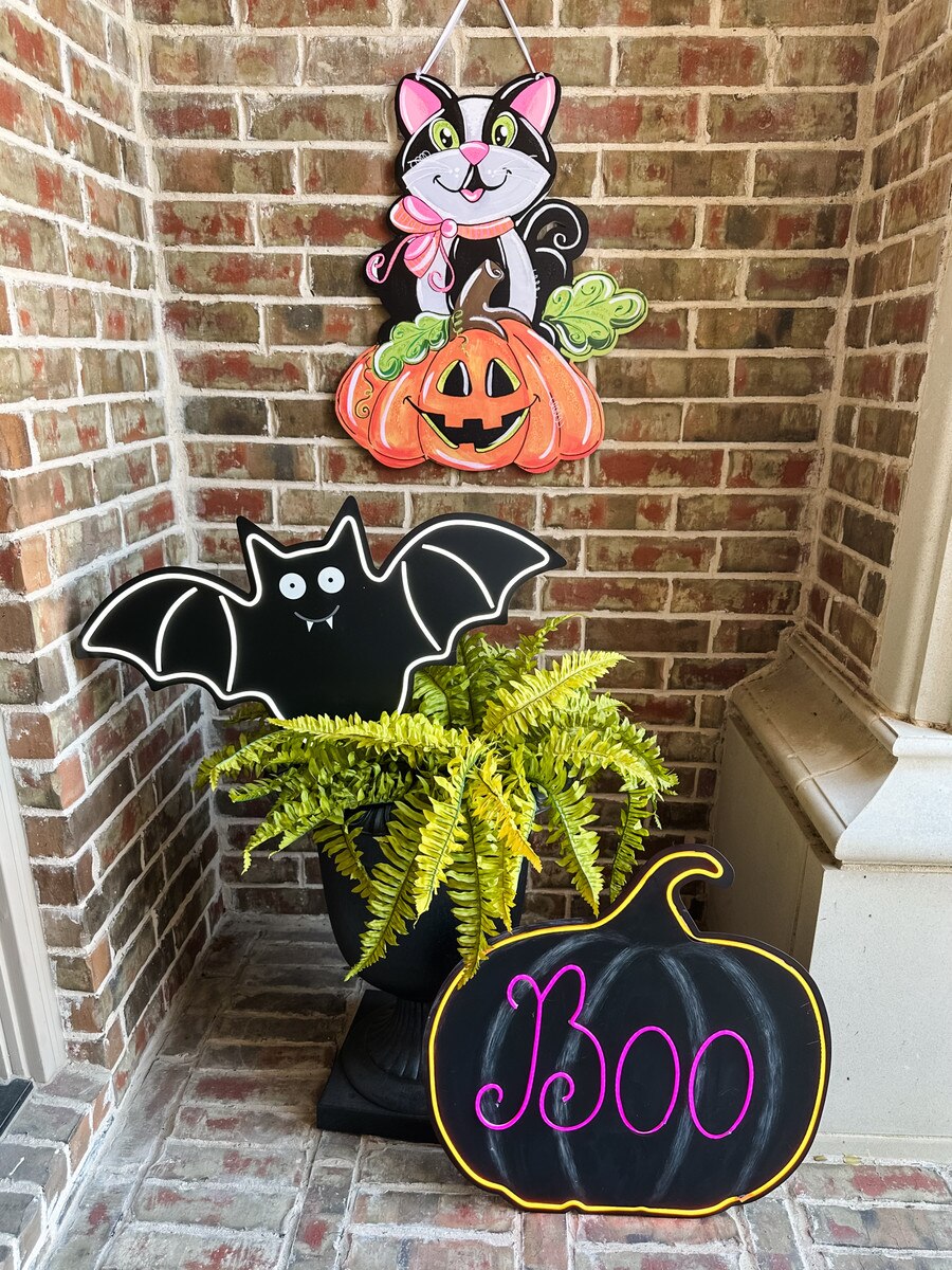 24-inch PVC Halloween door hanger featuring a black cat and orange jack-o'-lantern with whimsical Lori Martin artwork.