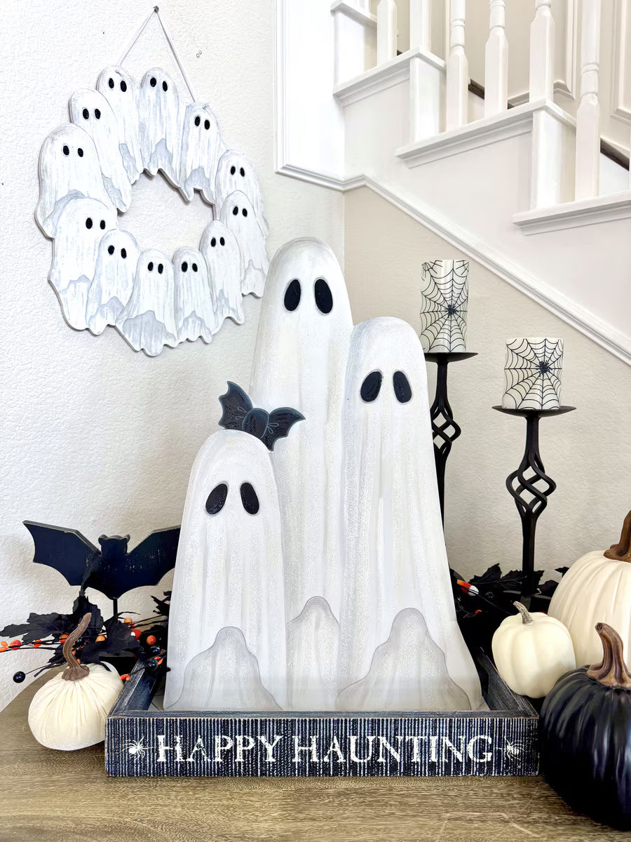 Large white ghost family trio decoration with black eyes and a bat accent, displayed in a Happy Haunting wooden tray.