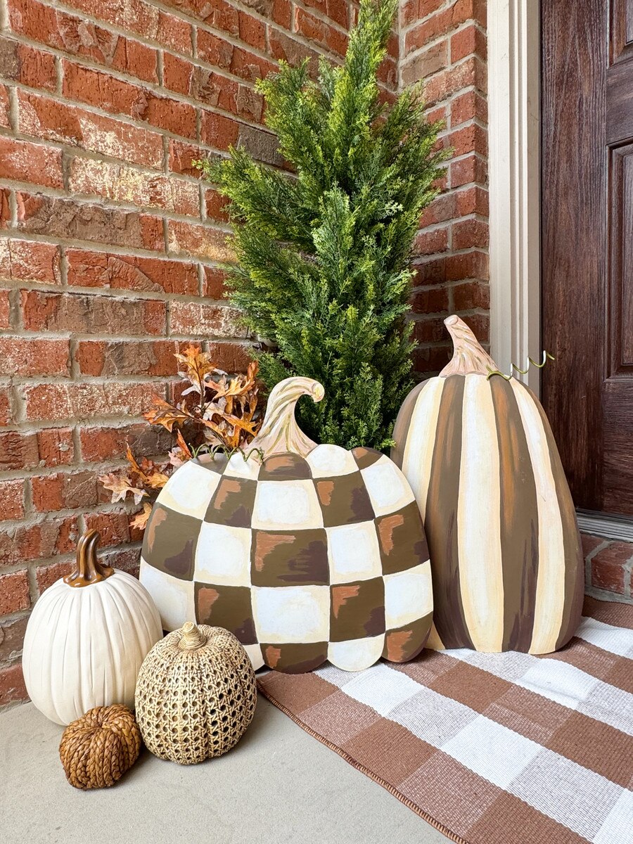 Decorative flat pumpkins with chocolate brown stripes and checkered patterns displayed on a porch for fall decor.