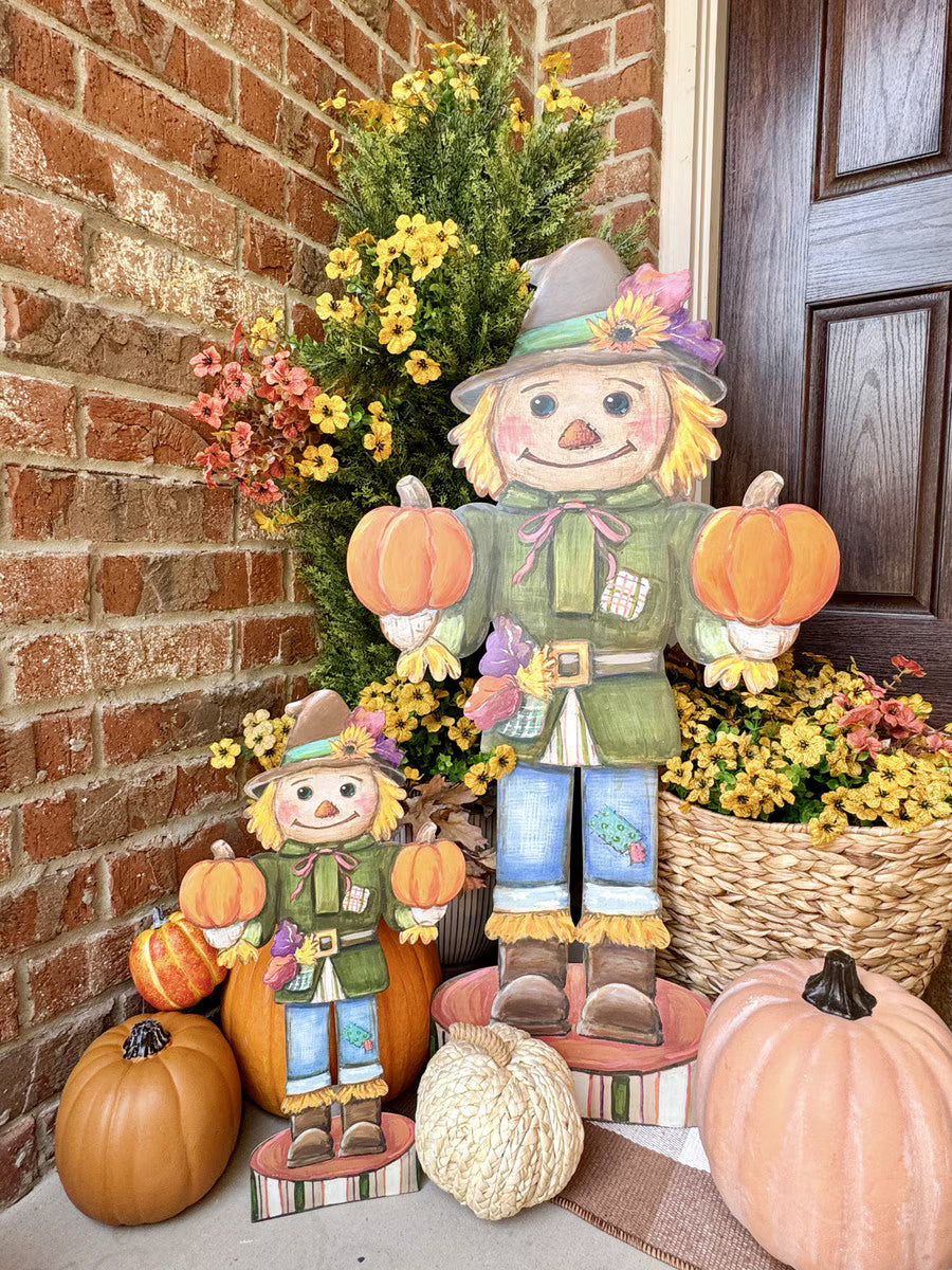 Whimsical scarecrow nutcracker wooden cutout holding pumpkins, featuring rustic autumn colors and a festive fall design.