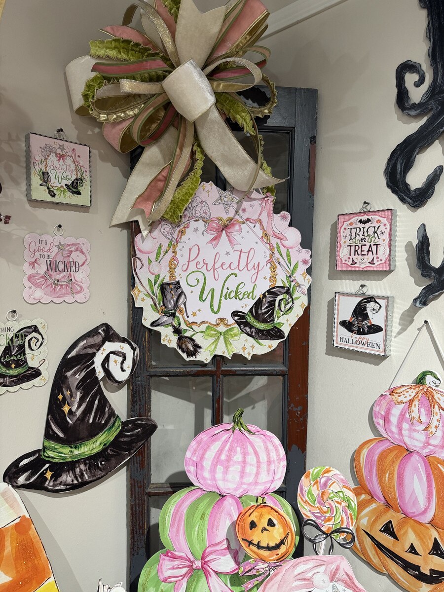 Perfectly Wicked PVC door hanger featuring a pink and green witch-themed design with a large decorative bow.