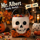 Bethany Lowe paper mache skull bucket with an orange glitter polka-dot bow tie, filled with Halloween candy.