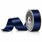 Navy blue satin acetate homecoming ribbon unspooling from cardboard core