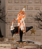 Vintage-style pumpkinhead clown in a polka-dot suit riding a black crow with glittered gold stars, 10.75-inch Halloween decor.