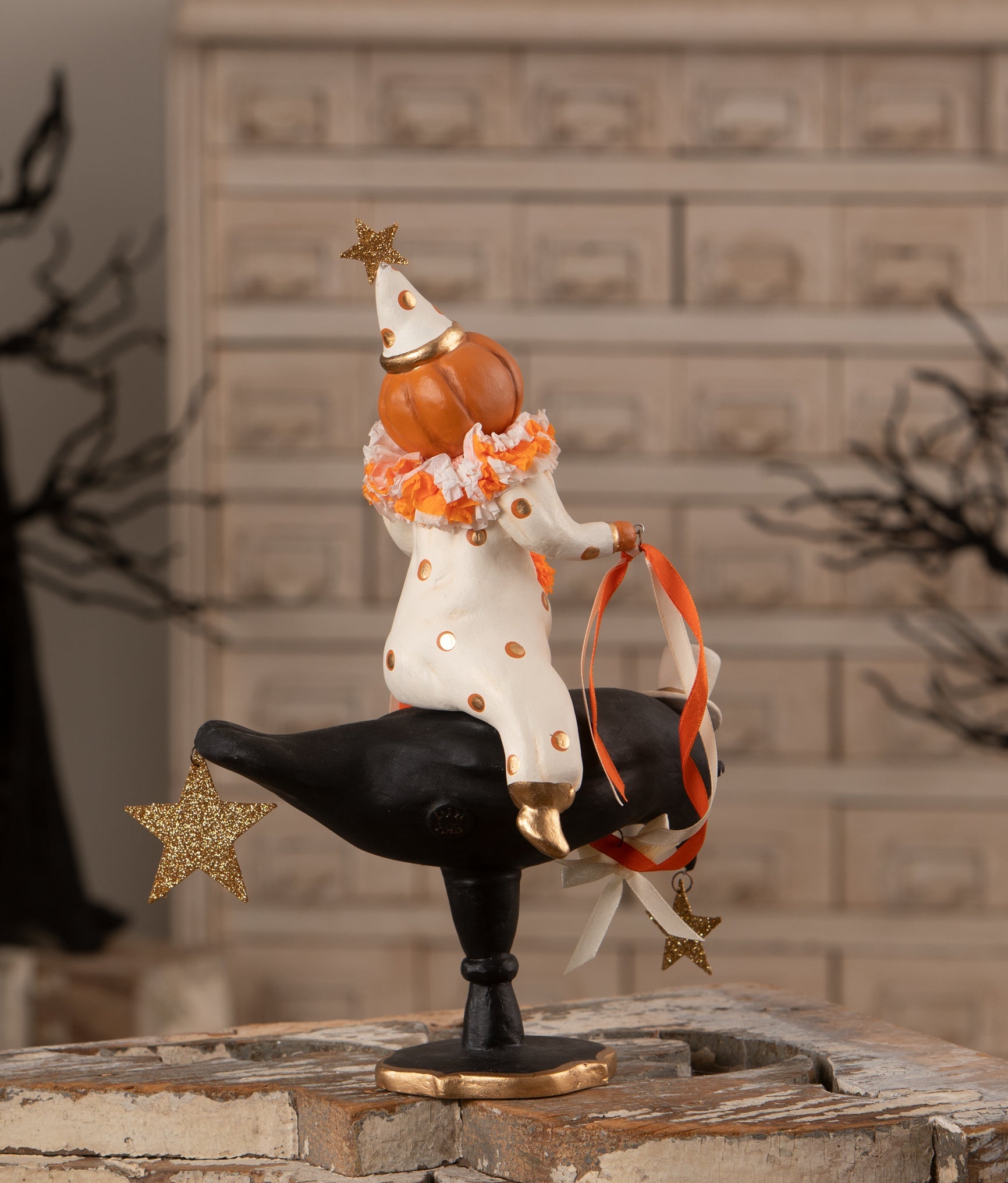 Vintage pumpkinhead clown in a polka-dot suit riding a black crow with glittered gold stars, 10.75-inch Halloween decor.