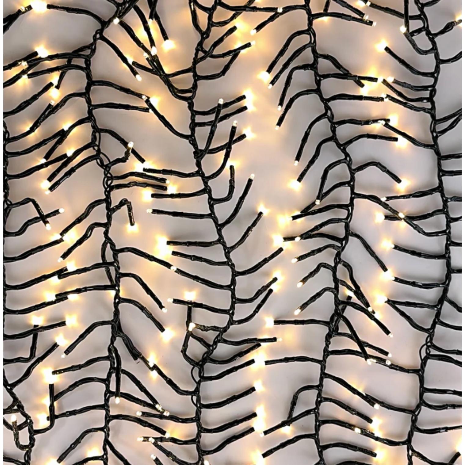 Close-up of dense warm LED twinkle light branches on dark green wire