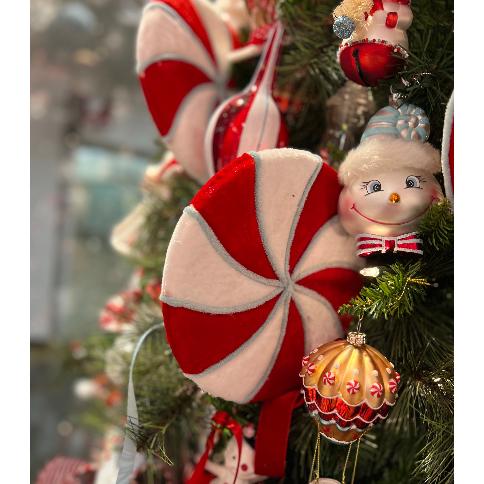 Red and white swirled peppermint lollipop stem ornament on Christmas tree