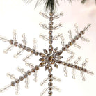 9-inch clear acrylic beaded snowflake ornament with faceted crystals hanging from a Christmas tree branch.