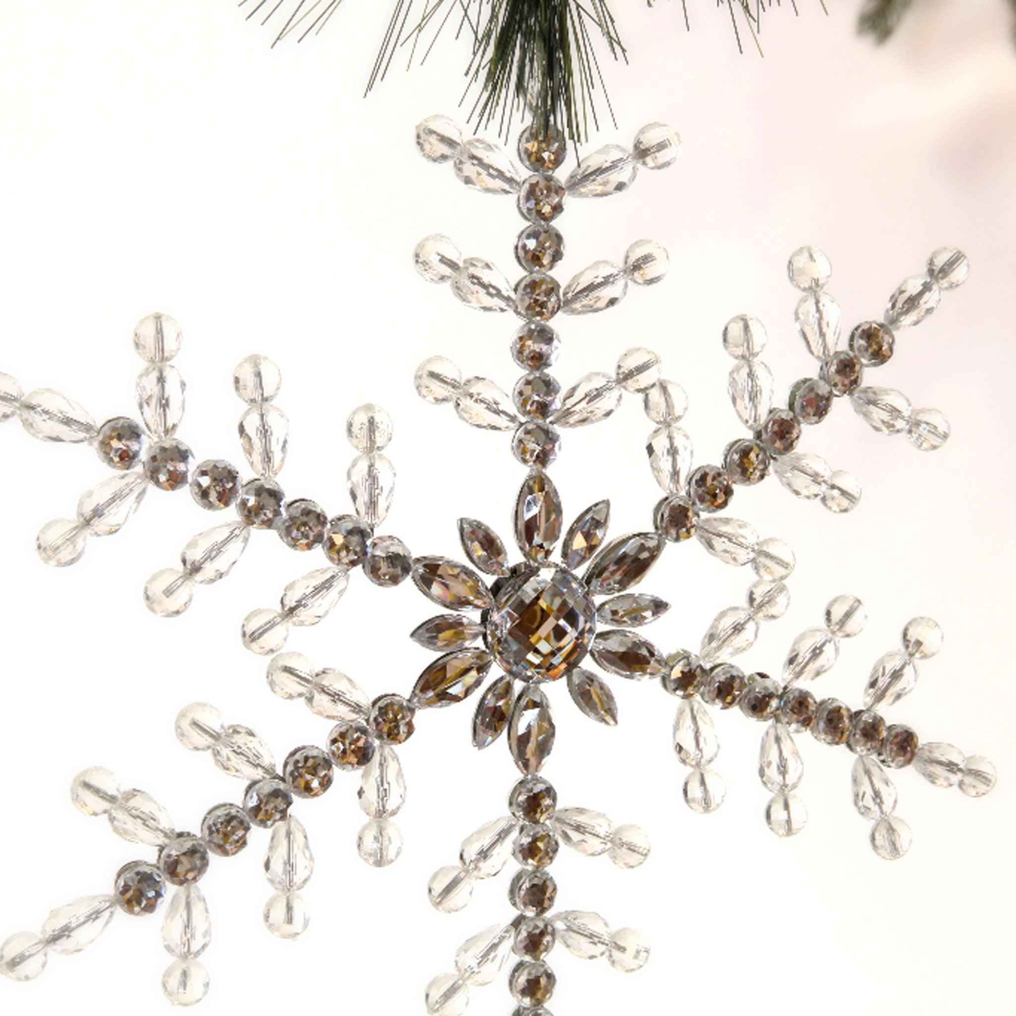 9-inch clear acrylic beaded snowflake ornament with faceted crystals hanging from a Christmas tree branch.