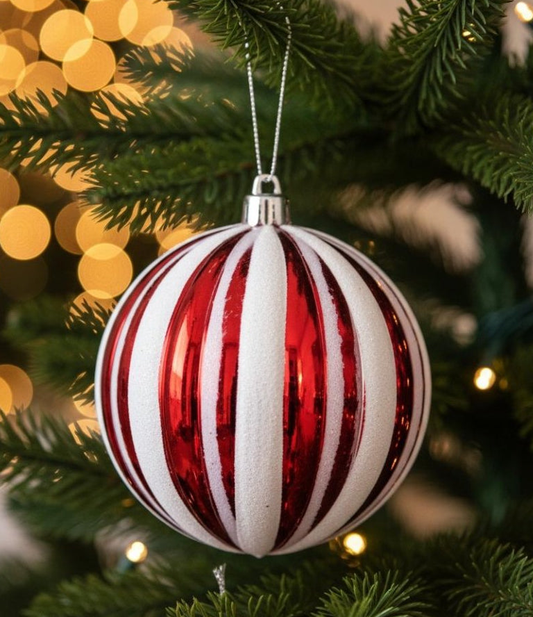 Red and white candy stripe ornament ball hanging on Christmas tree