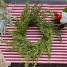 14-inch faux cedar mini Christmas wreath with realistic green foliage on a red and white striped farmhouse background.