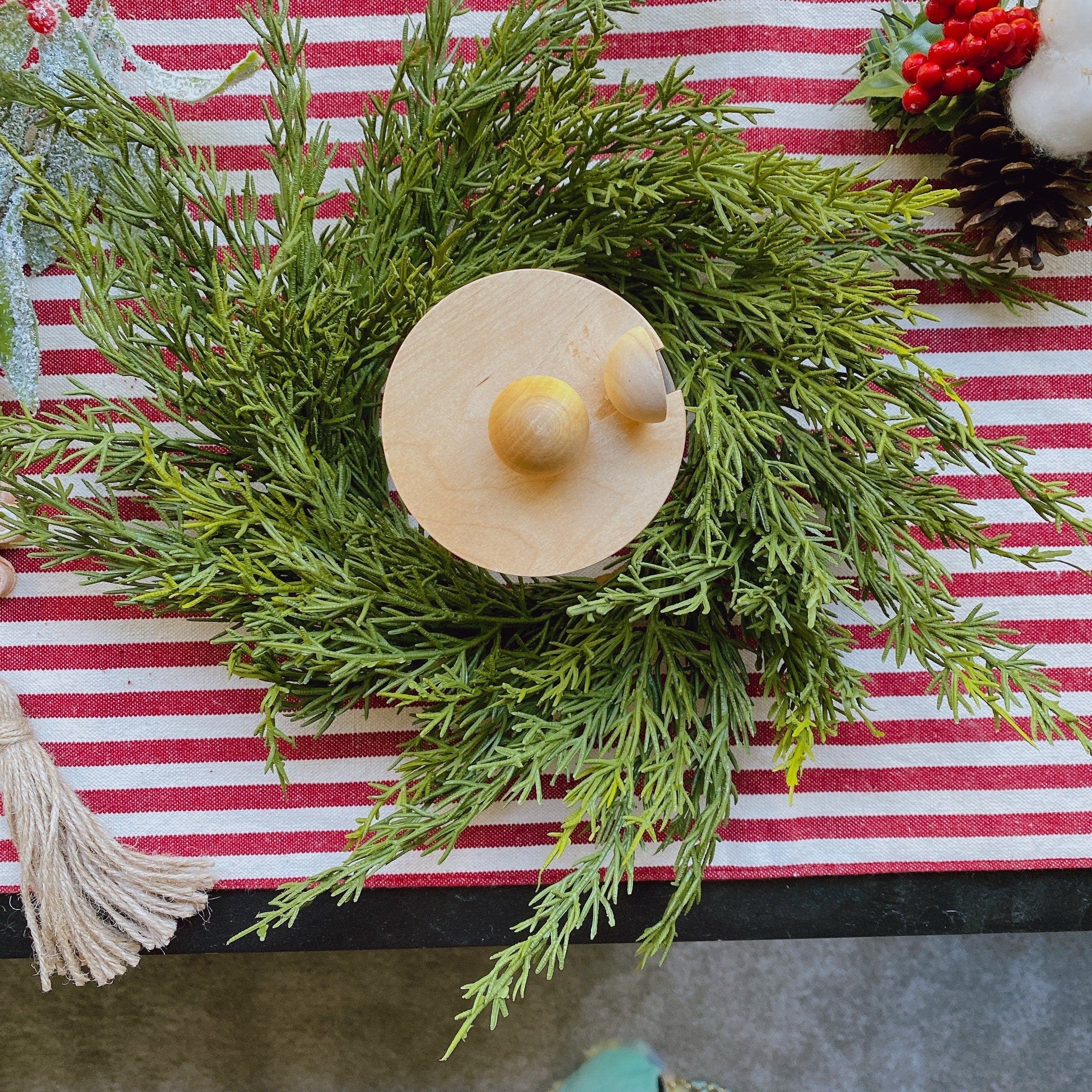 14-inch faux cedar mini Christmas wreath with green foliage on a red and white striped table runner.