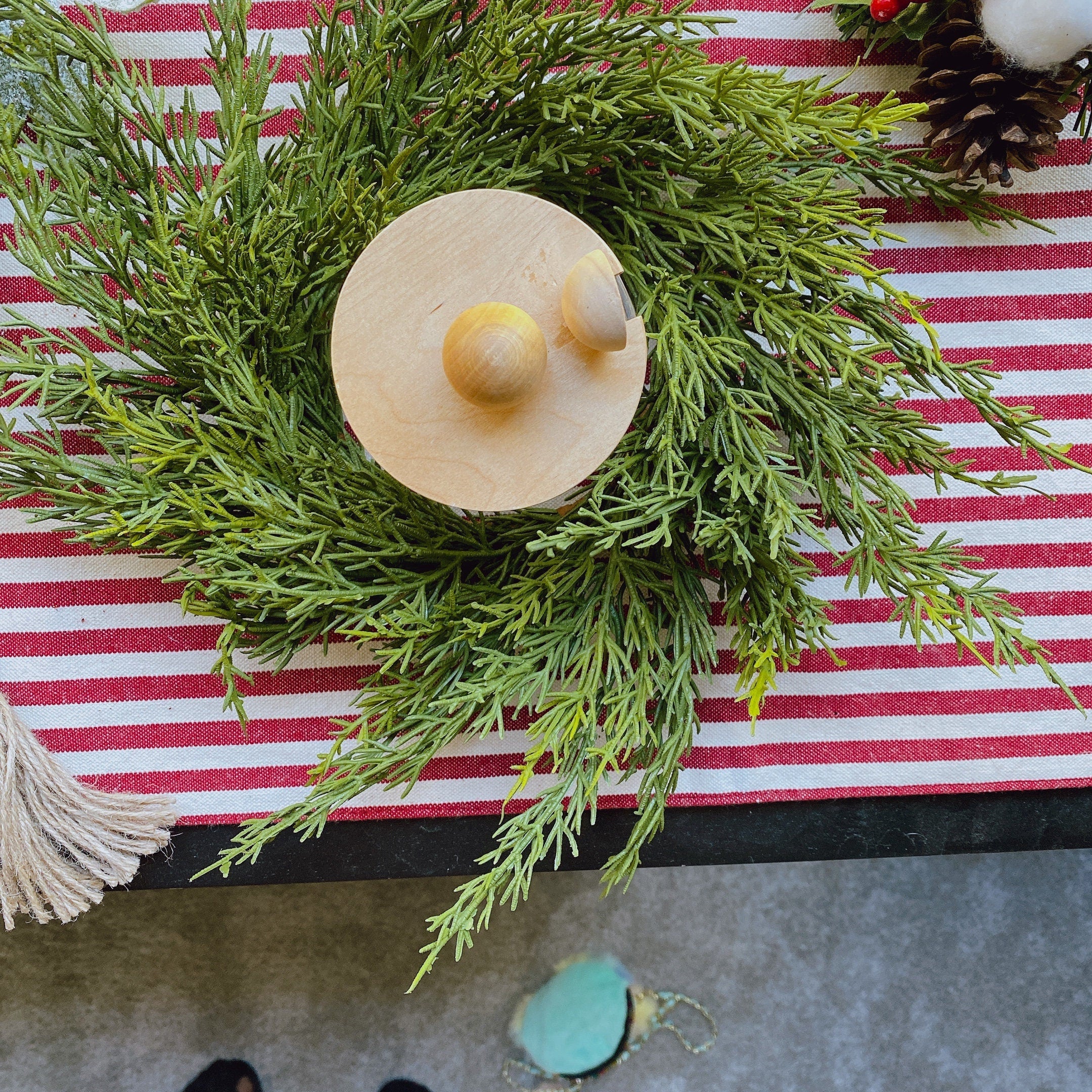 14-inch faux cedar mini Christmas wreath with a wooden accent on a red and white striped table runner.