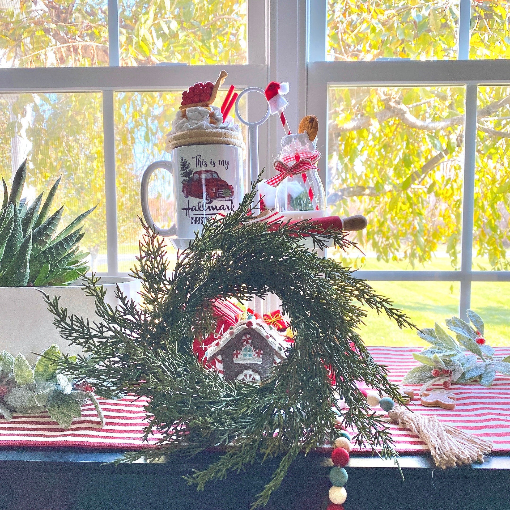 14-inch faux cedar mini Christmas wreath with realistic green foliage, styled as farmhouse holiday decor on a window sill.