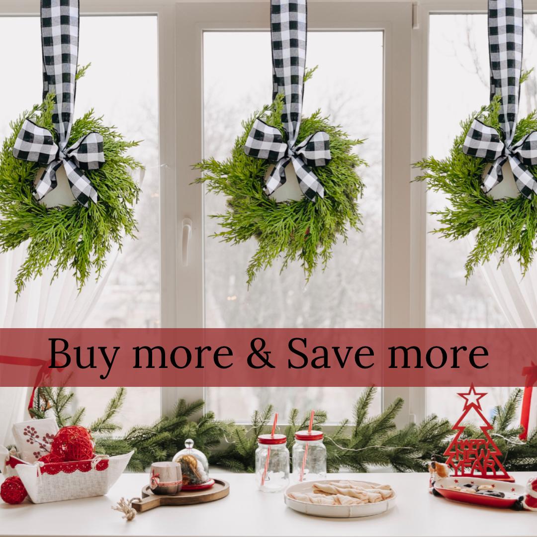Three mini artificial cedar wreaths hanging on a window with black and white buffalo check ribbons and bows.