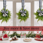 Three mini artificial cedar wreaths hanging on a window with black and white buffalo check ribbons and bows.
