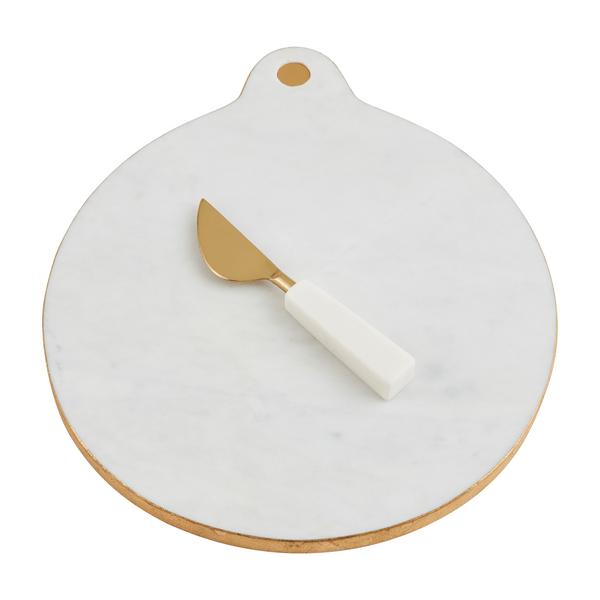 Round white marble serving board with gold foil edge and matching brass spreader with marble handle.